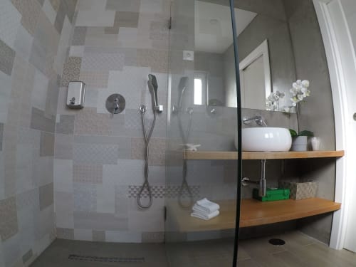 Modern bathroom with walk-in shower, wooden shelves, and white sink at Recantus Comporta, Comporta