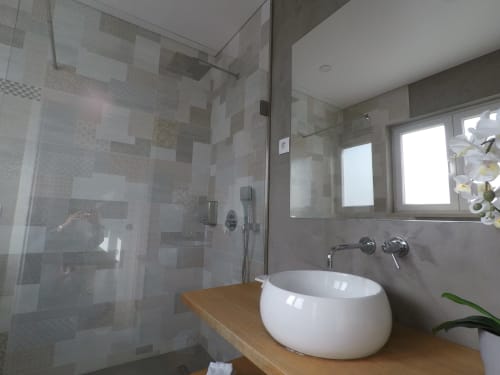 Modern bathroom in Egret Apartment at Recantus Comporta with round white sink, tiled shower, and garden views