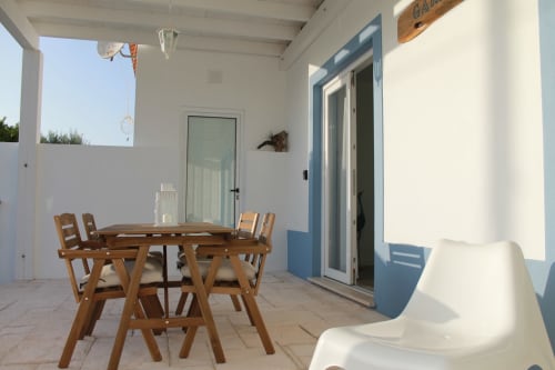 Egret Apartment terrace at Recantus Comporta with wooden dining table, chairs, and white lounger overlooking garden in
