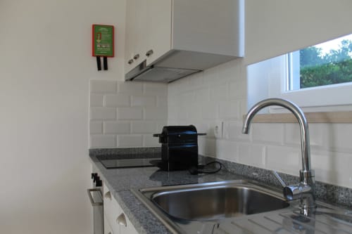 Modern kitchen in Egret Apartment at Recantus Comporta with stainless steel sink, gray countertop, subway tile backsplash,