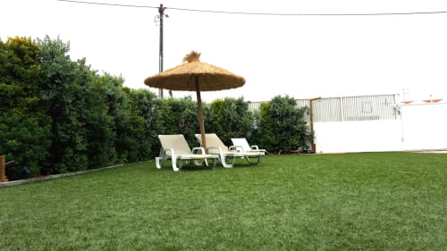 Recantus Comporta garden with loungers, thatched umbrella, and manicured lawn overlooking green hedges