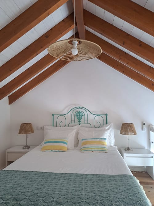 Bright bedroom in Stork Apartment at Recantus Comporta with exposed wooden beams, turquoise metal bed frame, striped pillows,