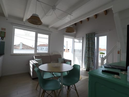 Bright modern living area in Stork Apartment at Recantus Comporta with dining table, green chairs, and city views