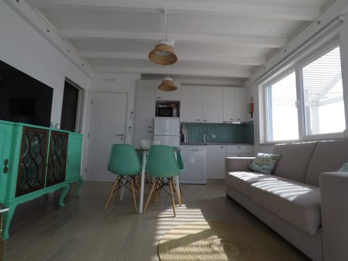 Stork Apartment living area at Recantus Comporta with green chairs, sofa, kitchen, and natural light