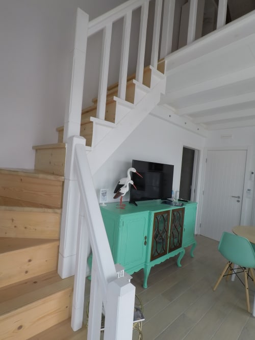 Stork Apartment living area at Recantus Comporta with turquoise TV console, white staircase, and modern seating in Comporta