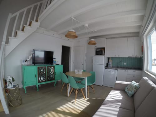 Bright open-plan apartment at Recantus Comporta with turquoise furniture, kitchen, dining area, and living room with TV and