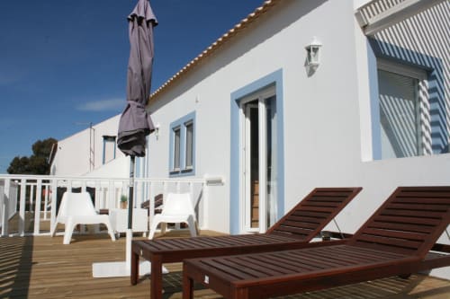 Stork Apartment deck at Recantus Comporta with lounge chairs, umbrella, and white modern building in Comporta
