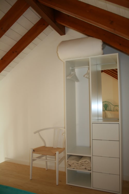 Stork Apartment bedroom at Recantus Comporta with white wardrobe, wooden chair, and exposed ceiling beams