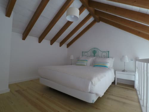 Bright attic bedroom at Recantus Comporta with wooden beams, white bedding, striped pillows, and wood flooring