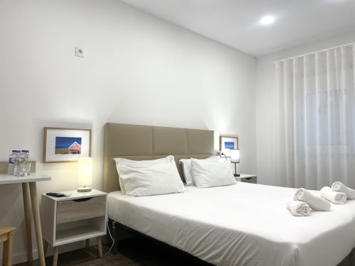 Quarto moderno de hostel na Vila Alexandra em Costa da Caparica com cama de casal, decoração neutra e roupa de cama branca