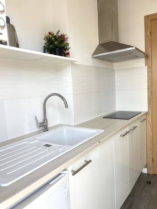 Modern kitchen at Vila Alexandra hostel in Costa da Caparica with white cabinetry, stainless steel sink, and gas cooktop