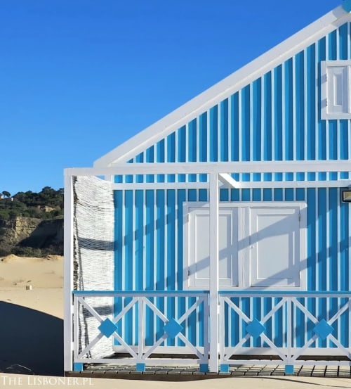 Vila Alexandra hostel beachfront building with blue and white striped facade in Costa da Caparica, Portugal