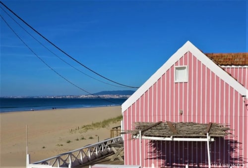 Red and white striped beach house at Vila Alexandra hostel in Costa da Caparica with sandy beach and ocean view