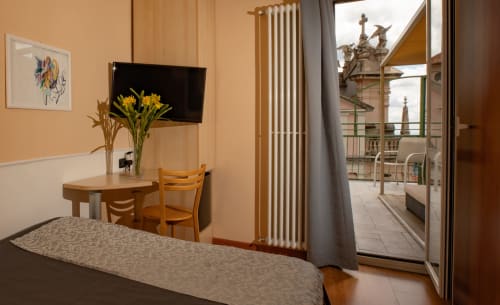 Camera Hotel Vista Lago con scrivania, fiori gialli e balcone con vista su Brunate, Italia