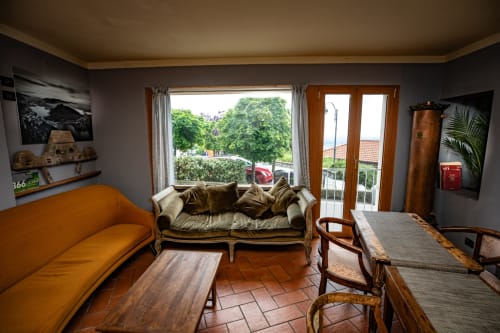 Soggiorno soleggiato dell'Hotel Vista Lago B&B a Brunate con divano color oro, divano verde oliva, mobili in legno e viste di lussureggiante vegetazione