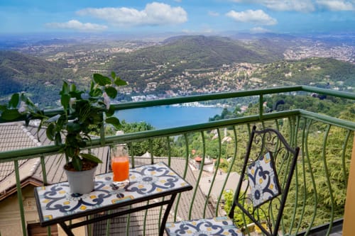 Terrazza dell'Hotel Vista Lago con pianta in vaso e succo d'arancia con vista sul lago di Como e sulle montagne di Brunate