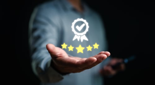 Personne tenant un badge d'excellence cinq étoiles et un symbole d'assurance qualité, représentant l'excellence de Home Horizon SBL à Limoges