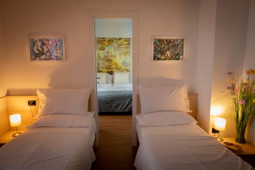 Due letti singoli con illuminazione calda in una camera moderna del cottage Hotel Vista Lago a Brunate, Italia, con vista lago