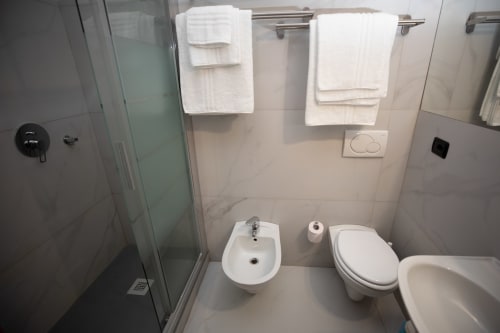 Bagno moderno dell'Hotel Vista Lago con doccia, toilette, bidet e asciugamani bianchi a Brunate