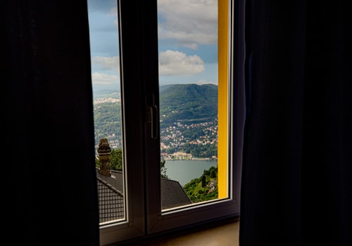 Vista del lago di montagna dalla finestra della camera dell'Hotel Vista Lago a Brunate, Italia, che domina le colline boscose e la riva del lago