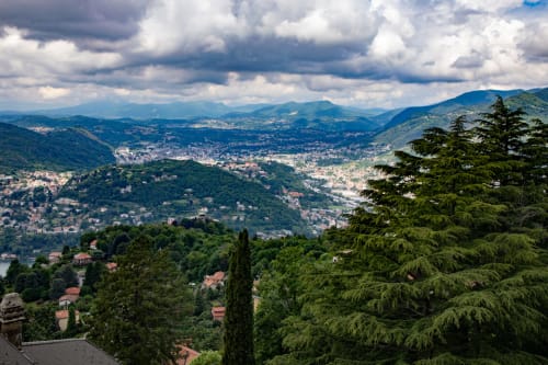 Vista panoramica delle montagne dall'Hotel Vista Lago a Brunate, Italia - fianchi boscosi, insediamenti nella vallata sotto un cielo drammatico
