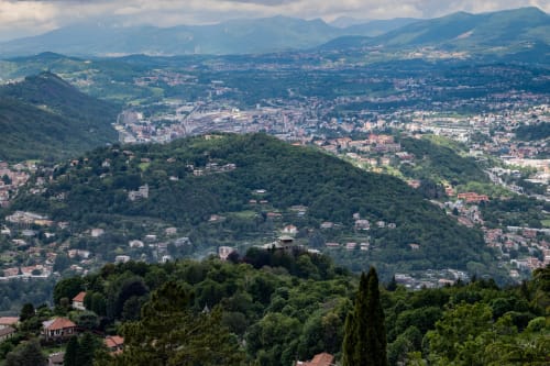 Vista aerea della valle di Brunate con montagne, colline boschive, edifici residenziali e paesaggio urbano dall'Hotel Vista Lago