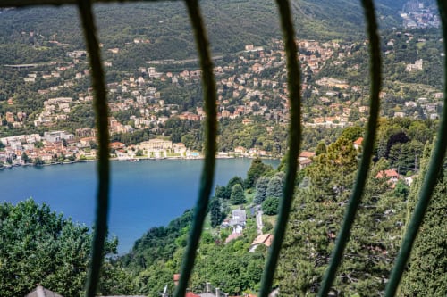 Vista del lago Como dal balcone dell'Hotel Vista Lago a Brunate, Italia con il paese in collina e villa sul lungolago