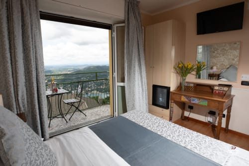 Camera d'albergo Vista Lago a Brunate con balcone vista lago, scrivania, TV e paesaggio montano