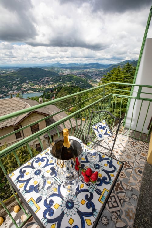 Champagne e fragole su un tavolo di balcone con vista sul Lago di Como e sulle montagne dall'Hotel Vista Lago a Brunate, Italia