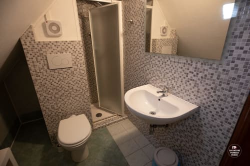 Bagno moderno dell'Hotel Vista Lago a Brunate con pareti in piastrelle mosaico, doccia, wc e lavabo arrotondato.