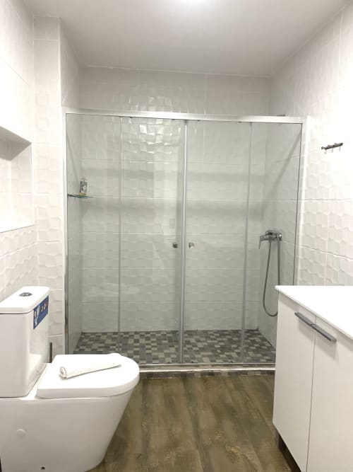 Modern bathroom with walk-in shower, white toilet, and wood-look flooring at Vila Alexandra hostel in Costa da Caparica