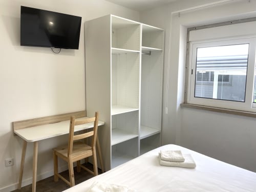 Praia Princesa room at Vila Alexandra hostel in Costa da Caparica with bed, desk, closet, TV and window view