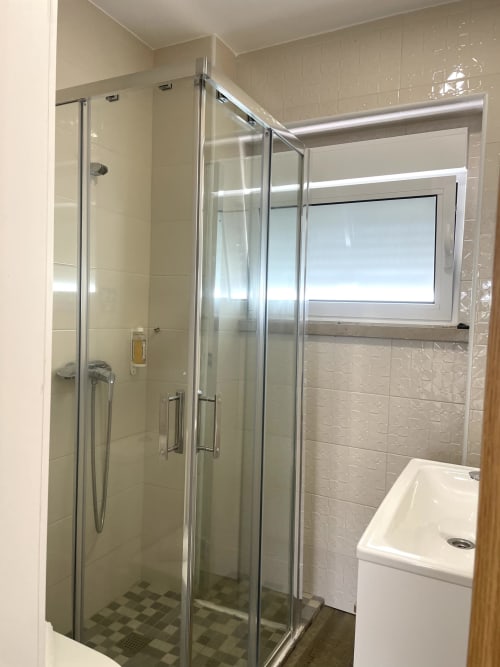 Modern shower enclosure with glass doors in Vila Alexandra hostel room, Costa da Caparica