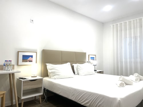 Modern hotel room at Vila Alexandra in Costa da Caparica with queen bed, neutral headboard, white bedding, and city view