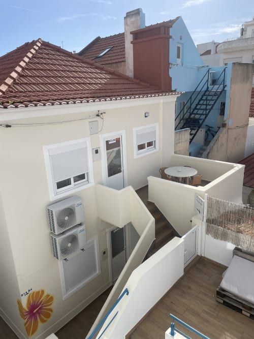 City view terrace at Vila Alexandra hostel in Costa da Caparica with AC units and furnished seating area