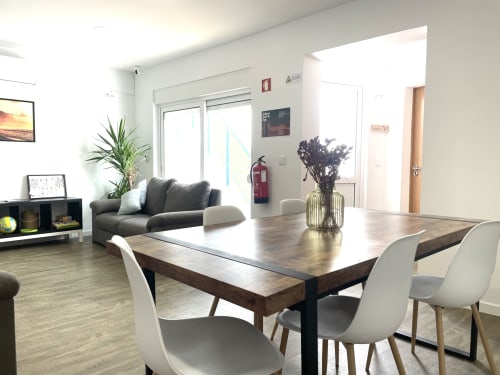 Modern hostel room at Vila Alexandra in Costa da Caparica with dining table, gray sofa, and contemporary furnishings