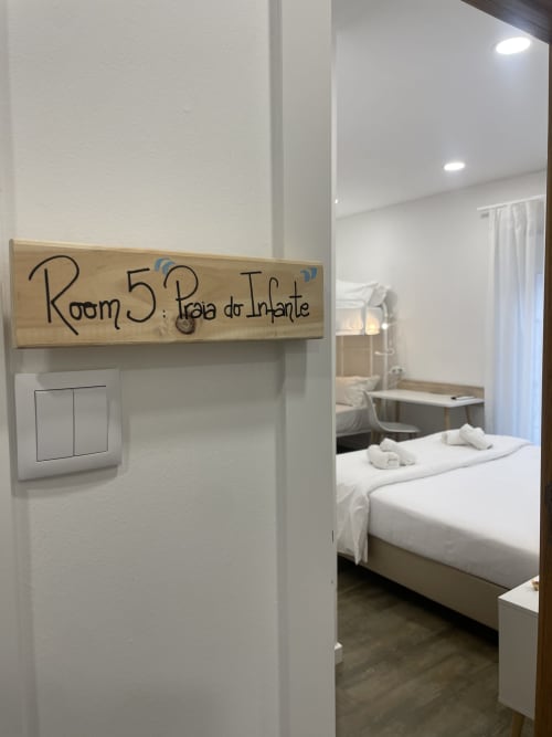 Room 5 Praia do Infante at Vila Alexandra hostel in Costa da Caparica with bed, modern decor, and wooden room sign