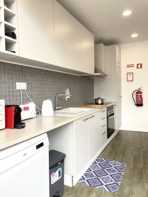 Modern kitchen in Vila Alexandra hostel room, Costa da Caparica with white cabinets, gray tile backsplash, and appliances