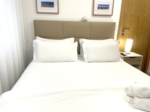 Clean double bed with white linens in Vila Alexandra hostel room, Costa da Caparica
