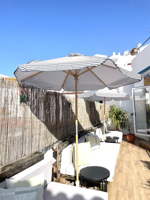 Striped umbrellas and white loungers on sunny terrace at Vila Alexandra hostel, Costa da Caparica Portugal