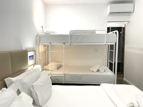 Clean hostel room at Vila Alexandra with single bed, bunk beds, TV, and air conditioning in Costa da Caparica