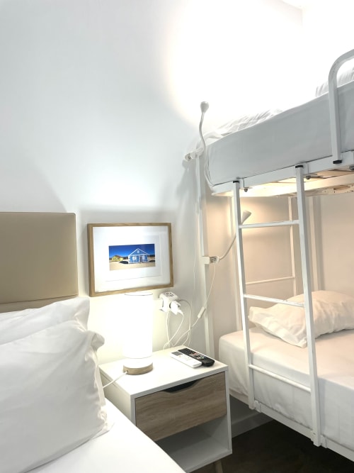 Bright hostel room at Vila Alexandra in Costa da Caparica with bunk beds, nightstand, and framed artwork