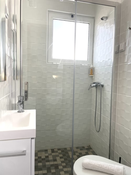 Modern bathroom at Vila Alexandra hostel in Costa da Caparica with glass shower enclosure and white vanity