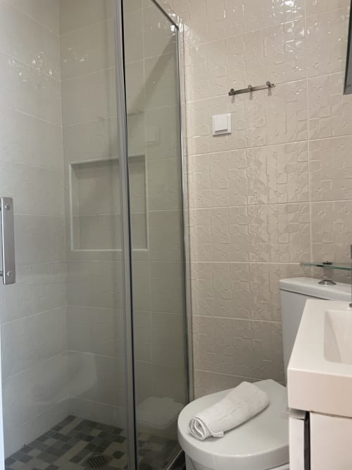 Modern bathroom with glass shower enclosure at Vila Alexandra hostel in Costa da Caparica, Portugal