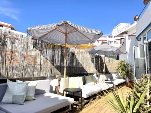 Rooftop terrace at Vila Alexandra hostel in Costa da Caparica with striped umbrellas, lounge seating, and city views