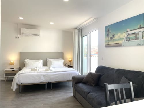 Modern bedroom at Vila Alexandra hostel in Costa da Caparica with queen bed, balcony access, sofa, and city views