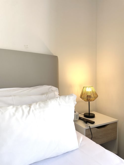 Modern bedroom at Vila Alexandra hostel in Costa da Caparica with white bedding, gray headboard, and warm lamp lighting