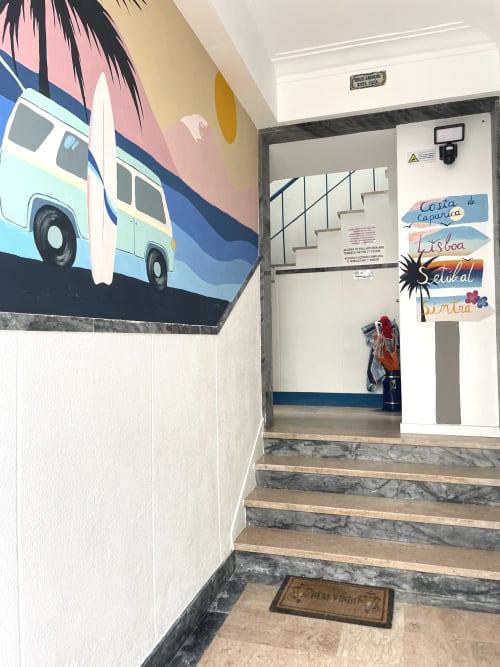 Stairwell entrance at Vila Alexandra hostel in Costa da Caparica with colorful bus mural and Portuguese destination signs.