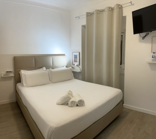 Modern hostel room at Vila Alexandra in Costa da Caparica with queen bed, TV, and ensuite bathroom