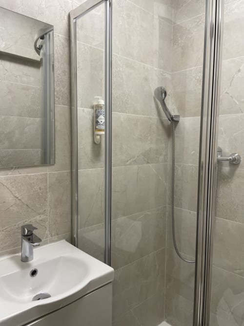 Modern bathroom at Vila Alexandra hostel in Costa da Caparica with tiled shower enclosure and white sink